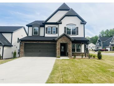 Charming two-story home boasts a stone-accented entrance and a two-car garage at 3284 Roundly Rd # 16, New Hill, NC 27562