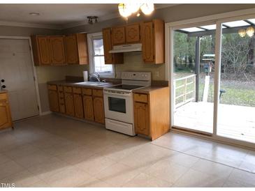 Traditional kitchen featuring ample cabinet space, a white range, and sliding door access to a patio at 7317 Bentley Wood Ln, Raleigh, NC 27616