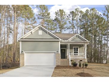 Charming one-story home with a welcoming front porch, attached garage, and well-maintained lawn surrounded by tall trees at 100 Sequoia Dr # 2387, Louisburg, NC 27549
