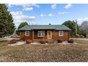 Charming log cabin with green roof, stone pathway, and landscaping at 1018 Lakeview Dr, Cedar Grove, NC 27231