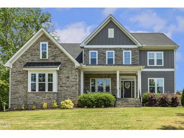 Beautiful home featuring a stone facade, covered porch, and lush landscaping creating great curb appeal at 1625 Banks View Dr, Raleigh, NC 27603