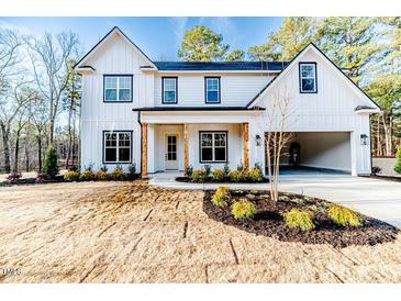 Two-story farmhouse with white siding, black accents and a three-car garage at 191 Landon Ridge, Sanford, NC 27330