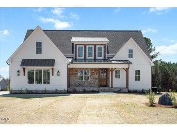 Charming two-story home with a brick porch and beautiful architectural details on a well-manicured lawn at 321 Bud Wall Rd, Youngsville, NC 27596