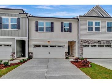 Charming townhome featuring a two-car garage, black shutters, and light beige siding at 7117 Hubner Pl # 22, Cary, NC 27519