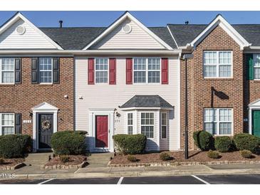 Charming townhome featuring red shutters, bay window, manicured landscaping, and convenient parking at 125 Watertree Ln, Apex, NC 27502
