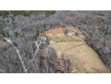 Expansive aerial view of a multi-building farm estate with fenced pastureland and surrounding woods at 7700 Circle L Trl, Rougemont, NC 27572