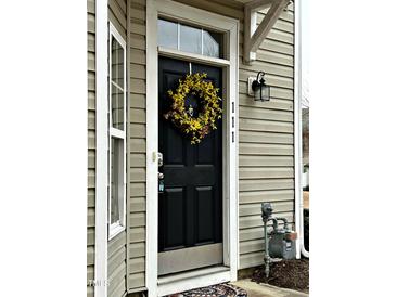 Inviting front door featuring a vibrant wreath and clear house numbers, complemented by neutral siding and trim at 1211 Canyon Rock Ct # 111, Raleigh, NC 27610