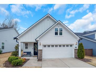 Charming white home featuring a two-car garage, a welcoming front porch, and well-maintained landscaping at 12408 Angel Vale Pl, Durham, NC 27703