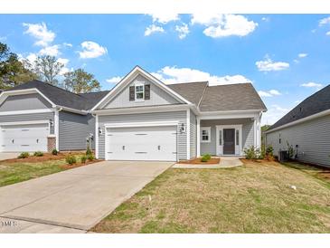Charming single-story home featuring a two-car garage, gray siding, and a well-manicured lawn under a bright blue sky at 209 Meadowbark Bnd # 20, Garner, NC 27529