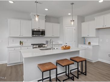 Bright kitchen featuring white cabinets, stainless steel appliances and a large island with stool seating at 3860 Well Fleet Drive, Fuquay Varina, NC 27526