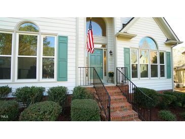 Charming home entrance with brick steps, black railings, and an American flag, set behind manicured landscaping at 107 Sir James Ct, Cary, NC 27513