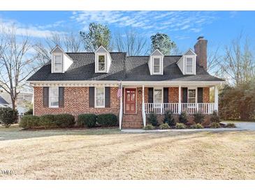 Charming brick home featuring dormer windows, shutters, and front porch with white railing at 2612 Hiking Trl, Raleigh, NC 27615