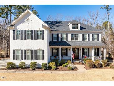 Two-story white brick home with black shutters, a porch, and manicured landscaping at 1141 Barley Stone Way, Raleigh, NC 27603