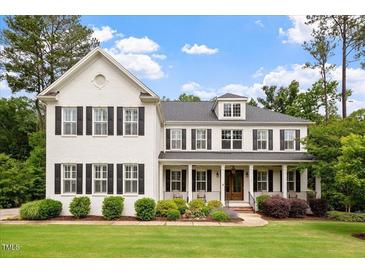 Charming two-story white brick home with black shutters, a covered porch, and a beautifully landscaped lawn at 1141 Barley Stone Way, Raleigh, NC 27603