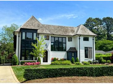 Stunning white brick home featuring black trim, gorgeous landscaping, and a meticulously maintained lawn at 1324 Brooks Ave, Raleigh, NC 27607