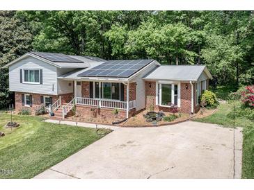 Charming brick home with solar panels, manicured lawn and flower beds at 326 W Bywood Dr, Durham, NC 27712