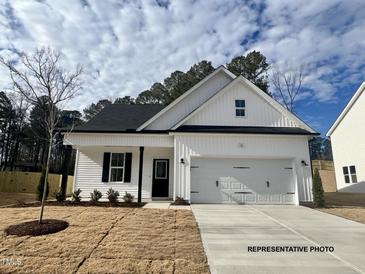 White house with black roof and two car garage at 371 Springtooth Dr, Zebulon, NC 27597