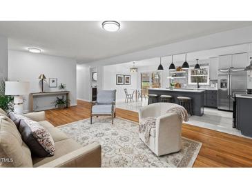 Open concept living room featuring hardwood floors, modern lighting, and an eat-in kitchen at 5232 Guess Rd, Durham, NC 27712