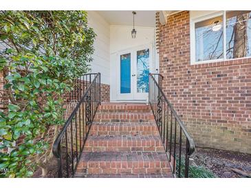 Charming brick home entrance with blue double doors, black railings, and lovely landscaping at 5410 Thayer Dr, Raleigh, NC 27612