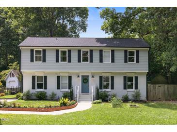 Charming two-story home with a blue door and a well-manicured front lawn at 106 N Trail Dr, Raleigh, NC 27615