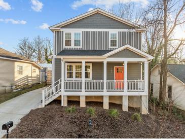 Charming two-story home featuring a covered front porch with a bright orange front door at 107 Bond St, Durham, NC 27707