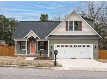 Charming home showcasing neutral siding, black roof, a two-car garage, and a welcoming peach-colored front door at 216 Cross St, Sanford, NC 27330