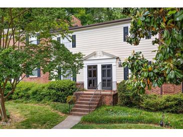 Charming exterior of a multi-level home showcasing brick steps, a covered entryway, and beautiful surrounding greenery at 3929 Browning Pl, Raleigh, NC 27609