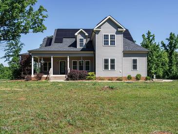 Charming two-story home featuring solar panels, a welcoming front porch and manicured landscaping at 3958 Buckhorn Rd, Sanford, NC 27330