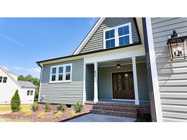 Charming home featuring a covered front entrance with craftsman details, a brick landing, and verdant landscaping at 83 Nottoway Lane, Wendell, NC 27591
