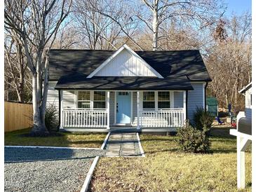 Charming home with a covered porch, blue front door, and landscaped front yard at 1210 Shaw St, Burlington, NC 27217