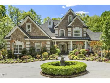 Beautiful brick home featuring manicured landscaping, a circular driveway, and classic architectural details at 209 Democracy Pl, Apex, NC 27523