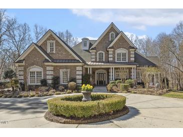 Stately brick home with manicured front yard, circular driveway, and covered front porch at 209 Democracy Pl, Apex, NC 27523