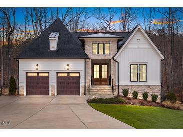 Elegant two-story home featuring a stone and white facade, complemented by a well-manicured lawn and mature trees at 227 Beech Slope Ct, Chapel Hill, NC 27517