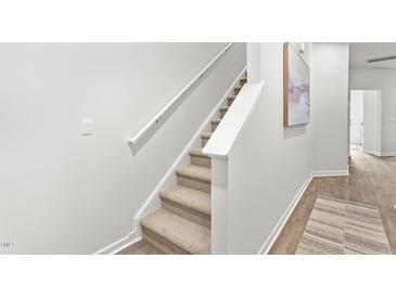 Carpeted staircase with white railings ascends to the next level in this neutrally decorated home at 280 Moyer Dr, Graham, NC 27253