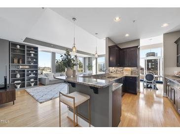 Modern kitchen featuring granite countertops, dark cabinetry, stainless steel appliances, and a breakfast bar with seating at 400 W North St # 730, Raleigh, NC 27603