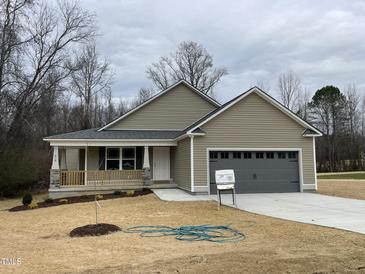 Charming single-story home featuring neutral siding, a welcoming front porch, and an attached two-car garage at 416 Magnolia Run Way, Benson, NC 27504