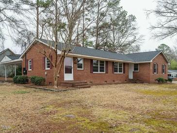 Charming brick home featuring red shutters, a well-manicured lawn, and mature trees at 431 Mattox St, Wendell, NC 27591