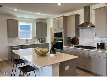 Bright eat-in kitchen with large island, modern appliances, light gray cabinets, and view of the window at 813 Emmer St, Rolesville, NC 27571