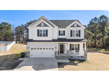 Charming two-story home with a two-car garage, a welcoming front porch, and attractive black and white exterior details at 99 Bodacious Ln, Benson, NC 27504