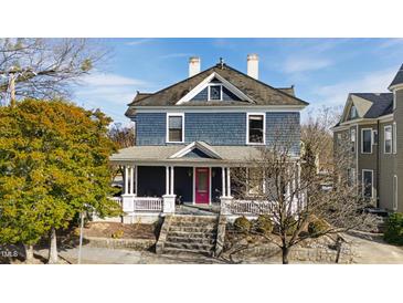 Charming two-story home featuring a welcoming front porch, gray siding and a vibrant pink front door at 101 S Bloodworth St, Raleigh, NC 27601