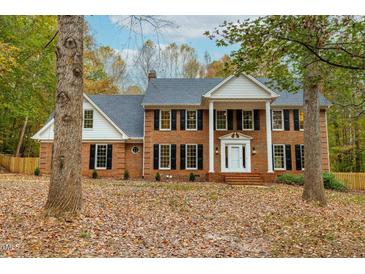 Stately brick home featuring a columned entrance and mature trees in a lush, leafy front yard at 11705 Appaloosa E, Raleigh, NC 27613