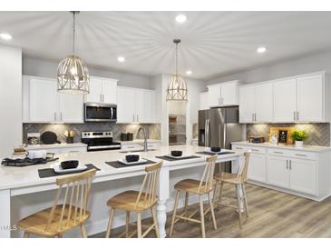 Bright kitchen features white cabinets, stainless steel appliances, and a large island with seating at 136 Cameron Willow Way Way, Angier, NC 27501