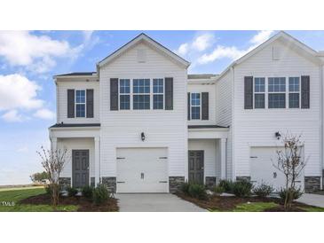 Charming townhome featuring a two-car garage, black shutters, and stone accents at 220 Starlight St, Sanford, NC 27330
