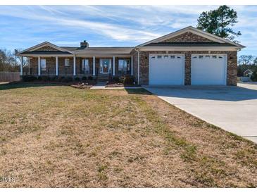 Charming brick home featuring a covered porch, two-car garage, and a well-maintained front yard at 2420 New Bethel Church Rd, Garner, NC 27529