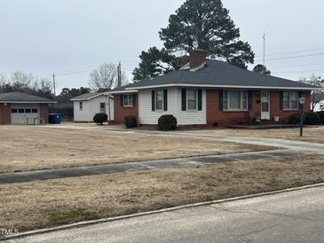 Charming single-story home featuring a brick and white wood facade, green shutters, and a well-manicured lawn at 405 N Wilson Ave, Dunn, NC 28334