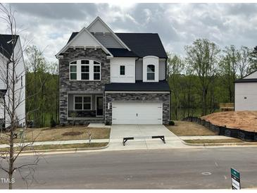 Charming two-story home with stone accents and a well-manicured front yard and attached two car garage at 4404 Emeline Way # 35, Fuquay Varina, NC 27526