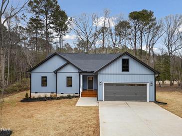 Charming single-story home showcasing a well-manicured lawn, a gray garage door, and light blue siding at 605 Shawnee Dr, Louisburg, NC 27549