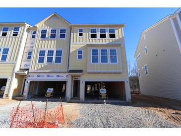 Two-story light yellow home with a two-car garage awaiting completion against a bright blue sky at 2317 Bay Minette Station Sta # 545, Apex, NC 27502