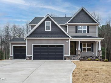 Charming two-story home with gray siding, dark roof, and a spacious three-car garage at 428 Hampshire Ct, Four Oaks, NC 27524