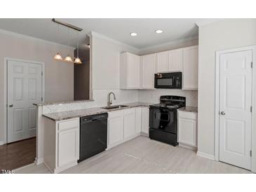 Bright kitchen features white cabinets, granite countertops, and black appliances at 650 Ganyard Farm Way # 13, Durham, NC 27703